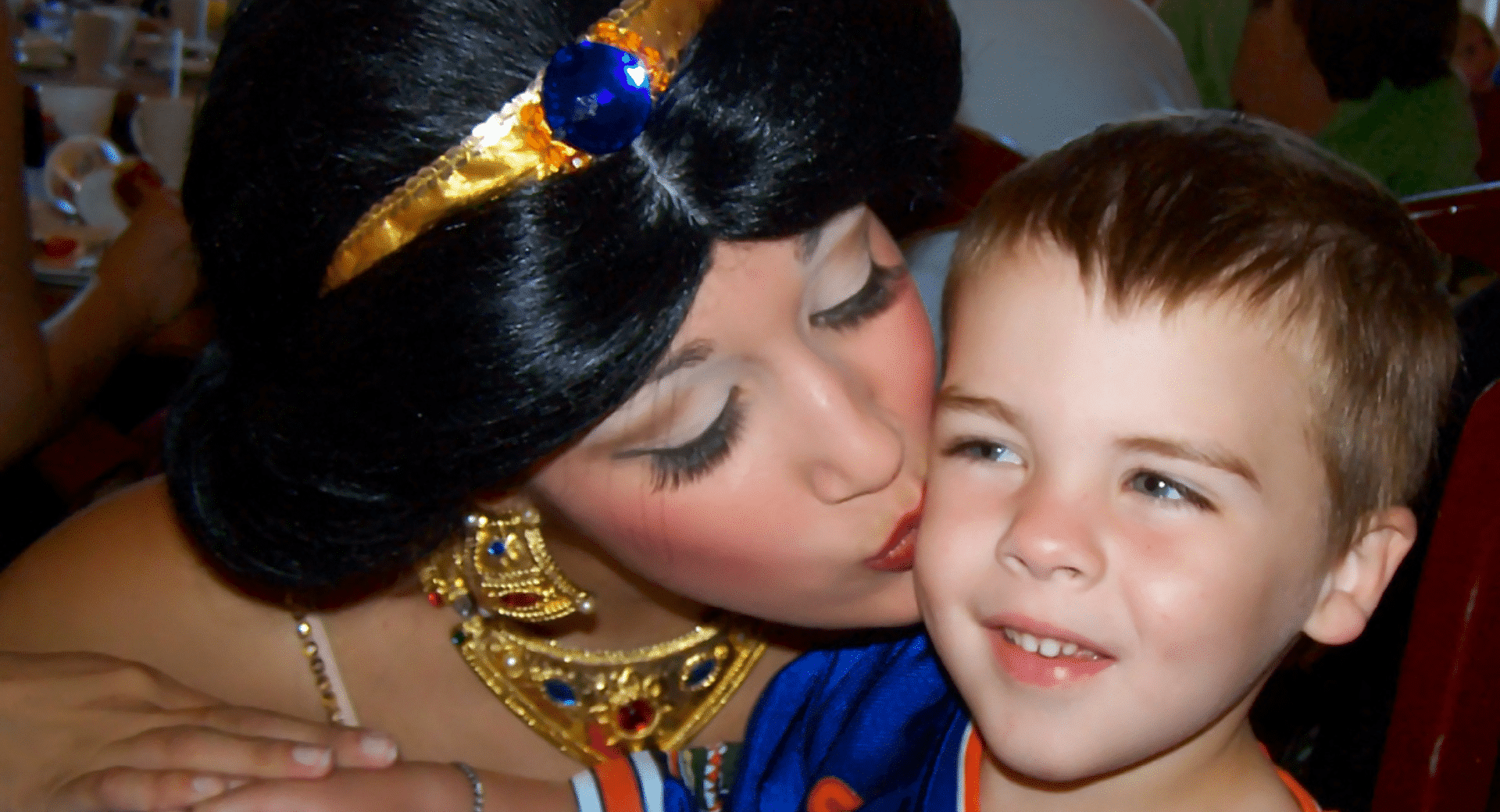A child getting kisses from Princess Jasmine at Walt Disney World's Epcot Center