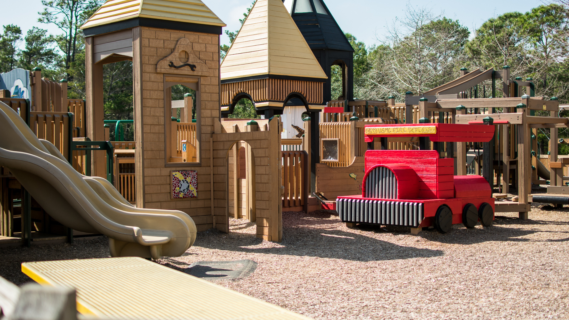 a playground with a red firetruck and a slide - Perdido Kids Park