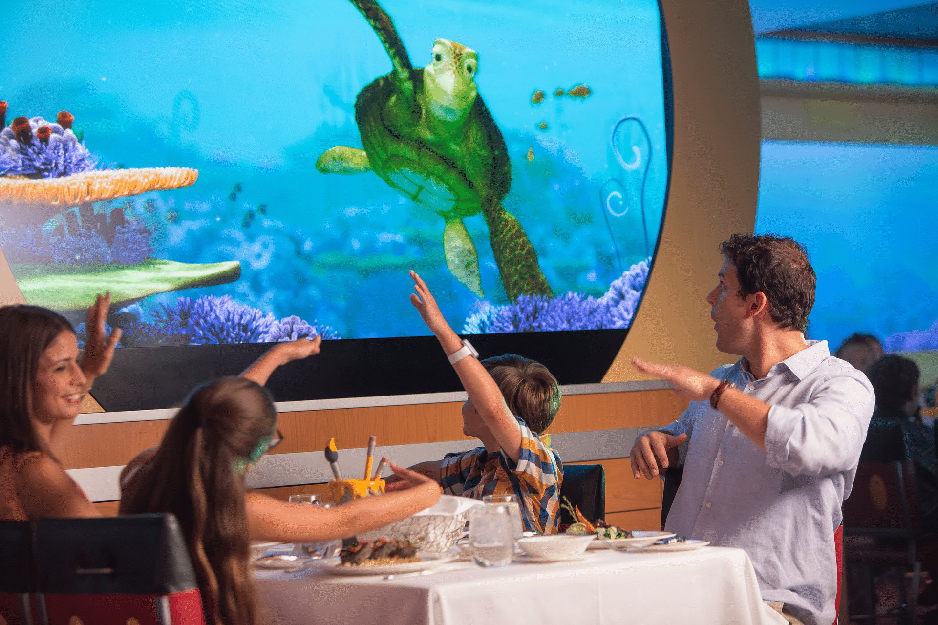 A Family aboard one of the Disney Cruise Line ships enjoying rotational dining by playing and eating with Crush at Animators Palette ©Disney