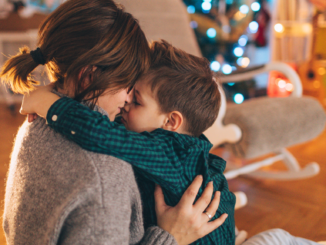 Single mom and son hugging in front of Christmas tree