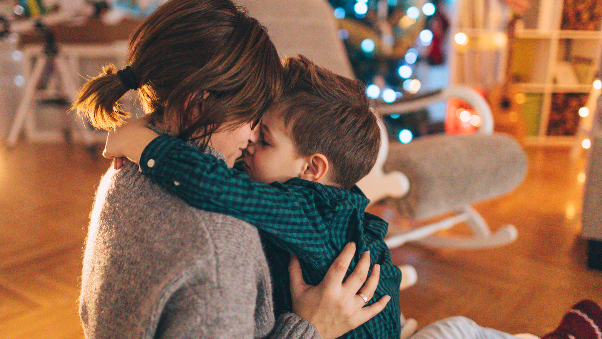 Single mom and son hugging in front of Christmas tree
